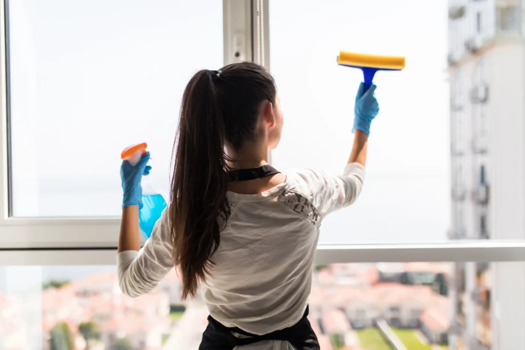 people-housework-housekeeping-concept-happy-woman-gloves-cleaning-window-with-rag-cleanser-spray-home